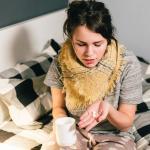 Donna con l'influenza a letto con tazza e medicine per il respiro