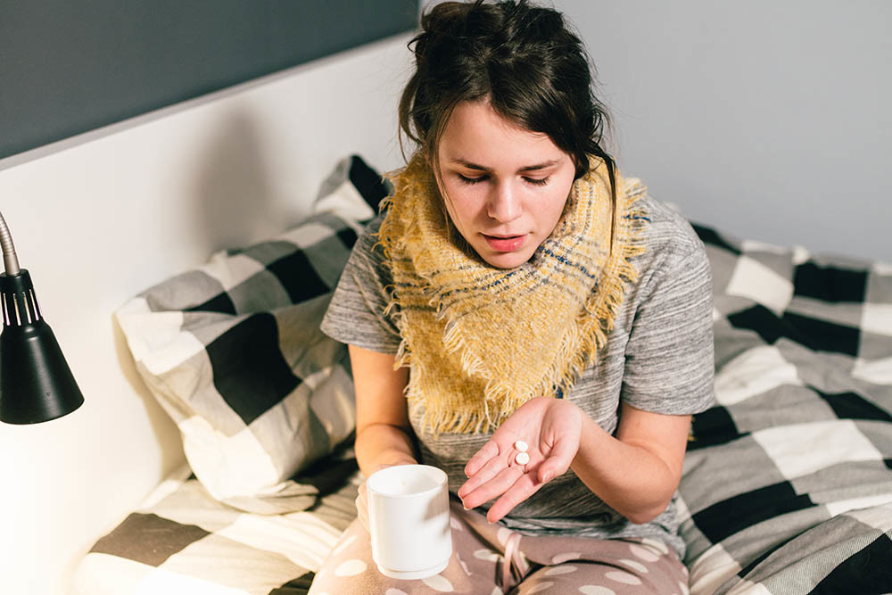 Donna con l'influenza a letto con tazza e medicine per il respiro